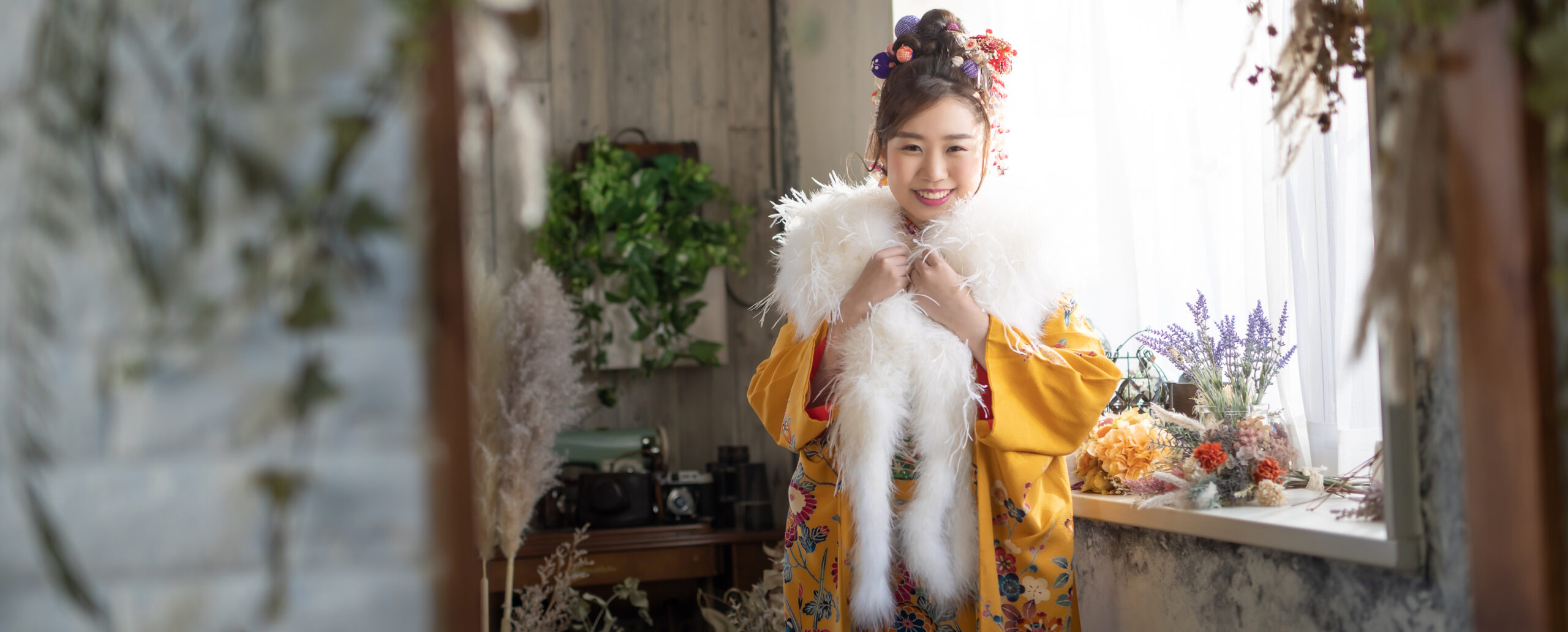 大分のPhotostudio PASSIONで、黄色の振袖と白いショール姿で笑顔を見せる成人式前撮りのスタジオ写真