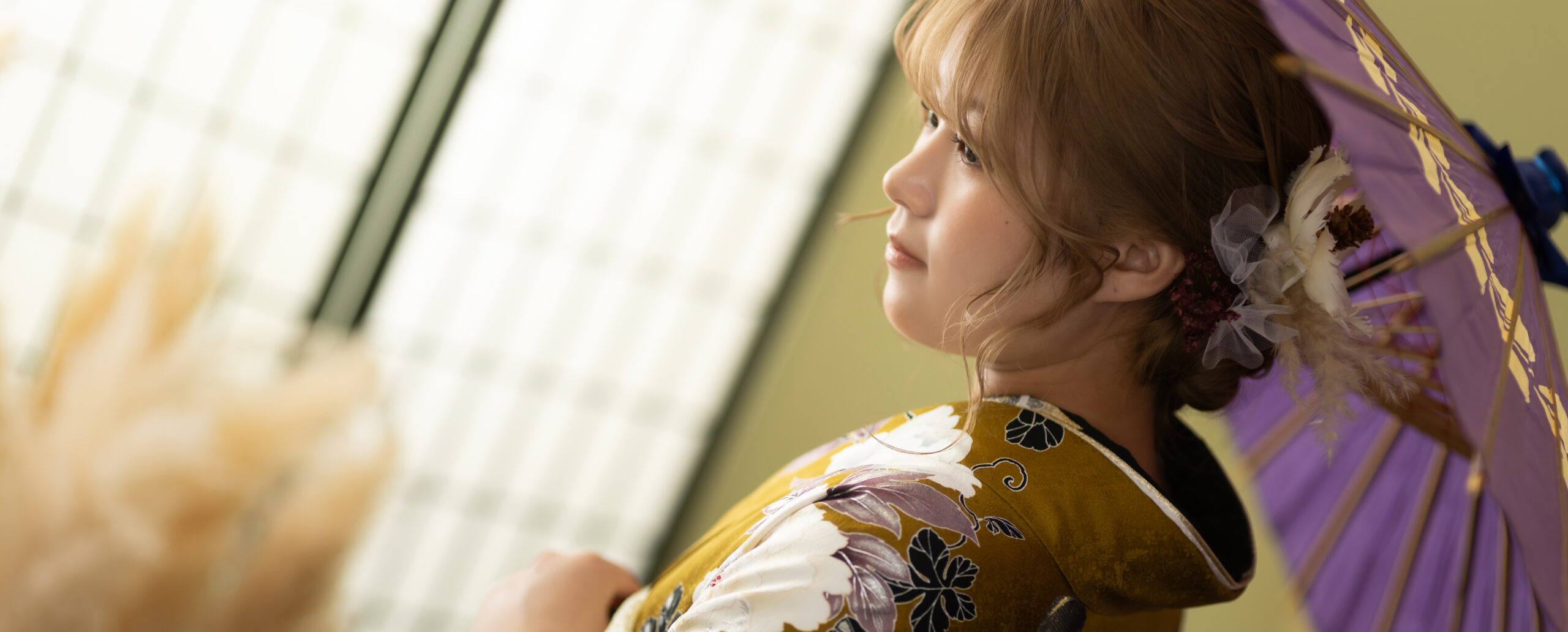 大分のPhotostudio PASSIONで、からし色の振袖に紫の和傘を合わせ、髪飾りと優しい横顔を美しく残した成人式前撮り写真