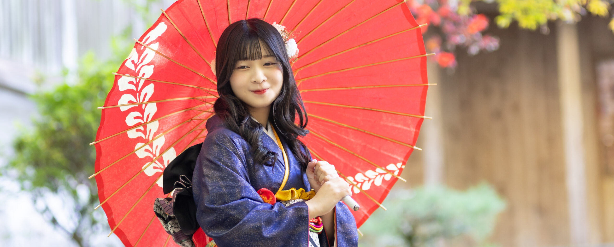大分西寒田神社で、紺色の振袖に赤い和傘を合わせ、華やかな髪飾りと柔らかな笑顔を残した成人式前撮り写真